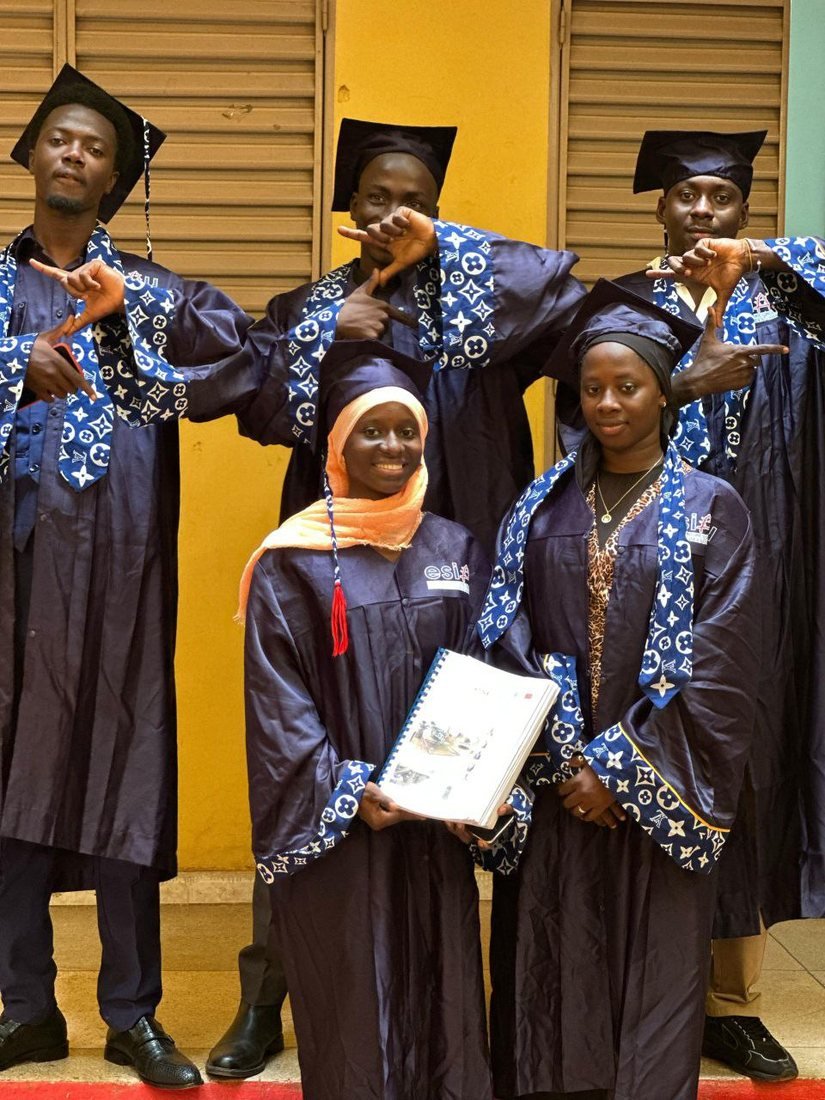 Cinq diplômés en toge bleue, dont l'un tient son mémoire
