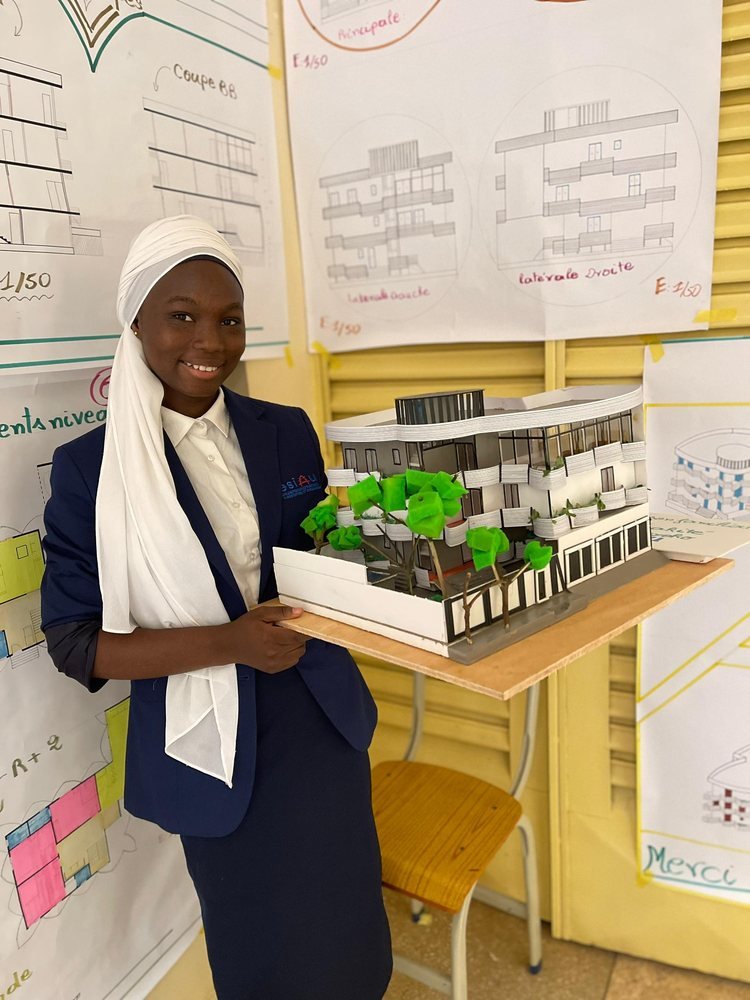 Une étudiante présente la maquette d'un bâtiment entouré d'arbres